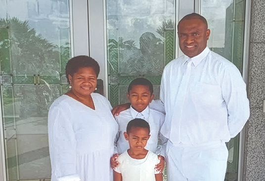 BYU-Pathway student Malakai Koroilagilagi from Fiji stands with his family outside the temple, posing together and smiling at the camera.