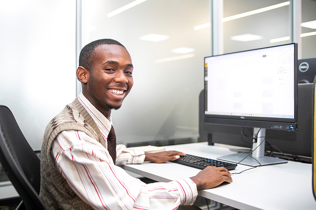 A student sits at a computer working on BYU-Pathway coursework.