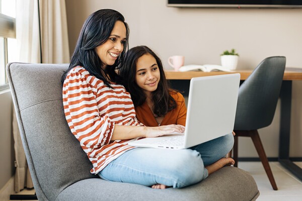 A mom studies on her laptop as her daughter watches.