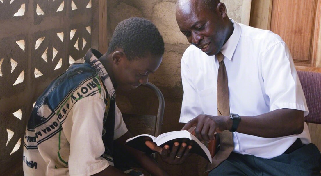 Two African men look at a book together