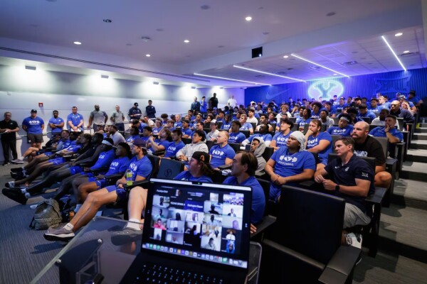 room full of football players sitting and listening to a presentation