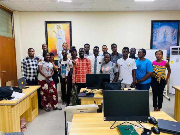 A group of African students stand together by computers