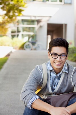 A college student sits outside, smiling