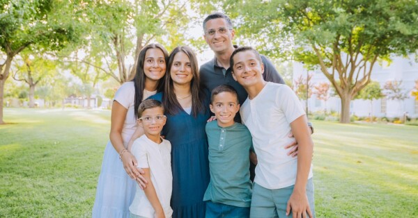 The Maia family, including Karine, her husband, and their four children, stand together, smiling, with their arms around one another.