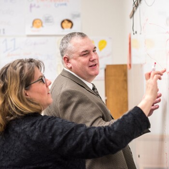 A teacher and a student at a BYU-Pathway gathering work on a project together.