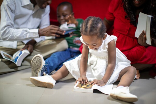 A young family from Nigeria smiling and experiencing spiritual growth as they read the scriptures together.