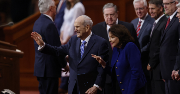 President Russell M. Nelson and Sister Wendy Watson waving to audience members in the conference center.