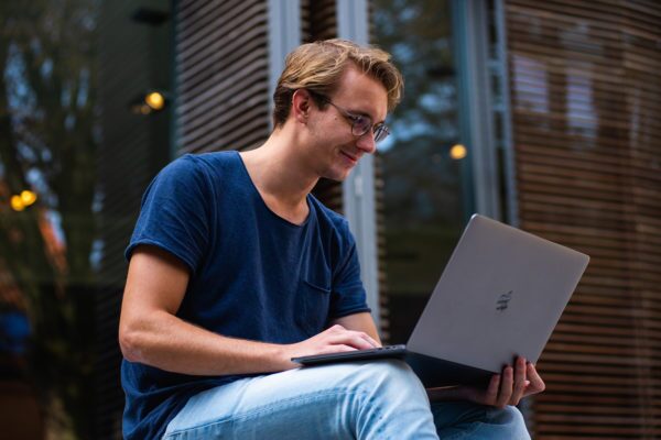 Young man wearing glasses looks at his laptop