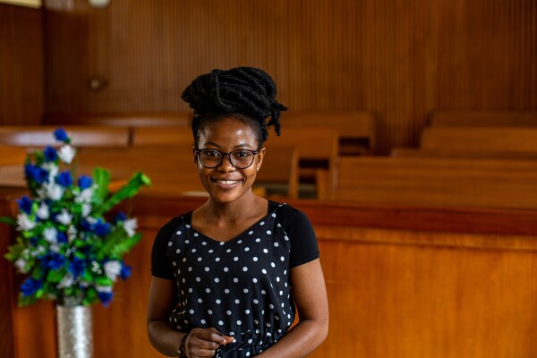 A woman smiles at the camera from inside a church