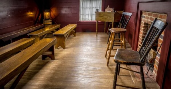 A replica of the school of the prophets schoolroom with benches, chairs, a fireplace, and a writer’s desk.