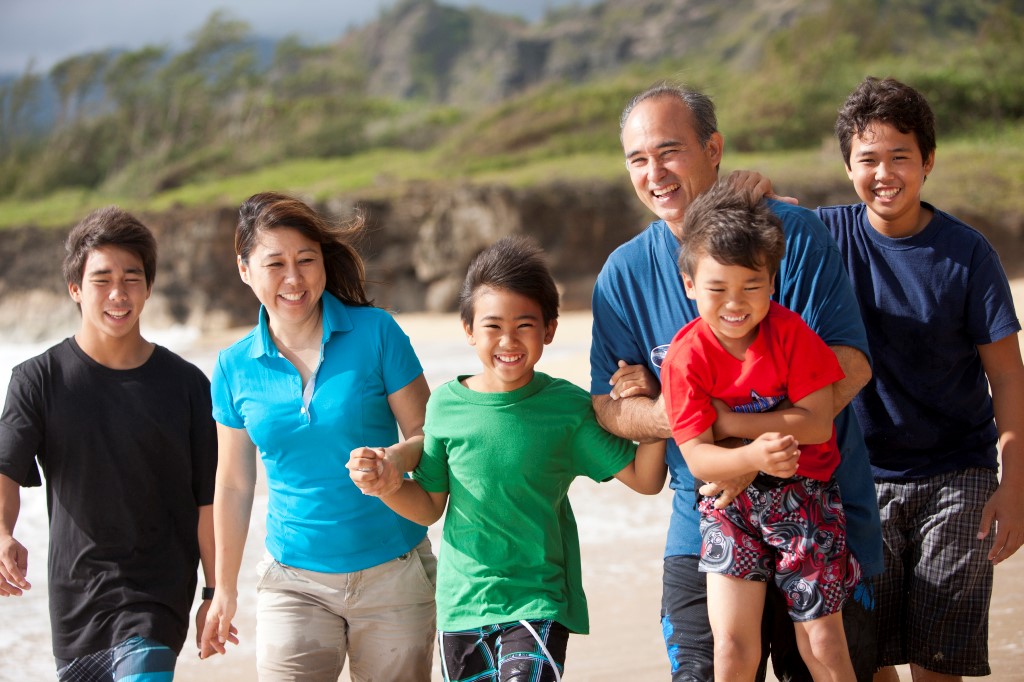 A family walking on a beach and holding hands.